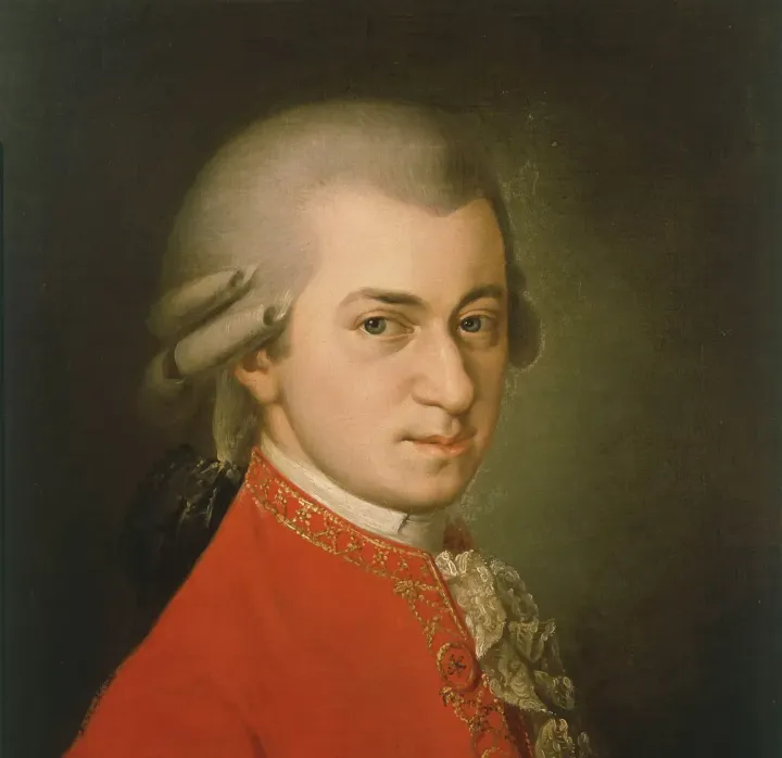 An oil painting of Mozart, who looks straight at the viewer and is wearing a red formal coat.